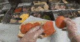 a person wearing plastic gloves is preparing a sandwich