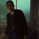 a man in a suit stands in front of a window