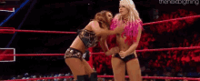 two women are wrestling in a ring while a referee looks on .