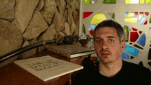 a man sitting in front of a stained glass window with a book on the table that says ' samurai ' on it