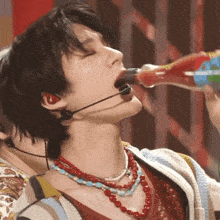 a man with a microphone in his ear drinking from a bottle