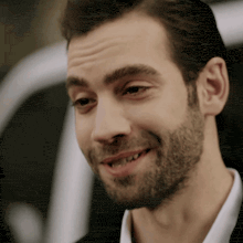 a man with a beard and a white shirt is smiling