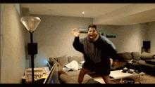 a man dancing in a living room with a lamp