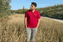 a man in a red polo shirt is standing in a field of tall grass