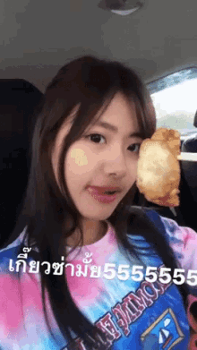 a girl in a tie dye shirt is holding a piece of food in her hand