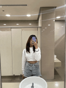 a woman taking a selfie in a public bathroom