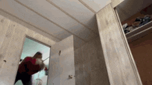 a person in a red shirt is standing in a room with a white door