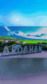 a sign that says ardahan in front of a green field