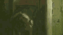 a clown is sitting in a chair in a dark room holding a piece of paper .