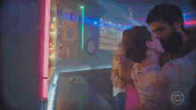 a man and a woman are kissing in a dark room with neon lights