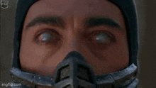 a man in a ninja costume is standing in the woods and saying come here .