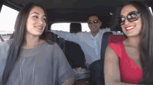 a man and two women are sitting in a car