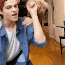 a man in a denim shirt is holding another man 's hand