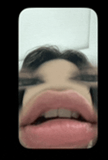 a close up of a woman 's face with glasses and pink lips .