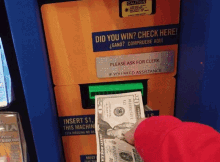 a person takes a twenty dollar bill out of a machine