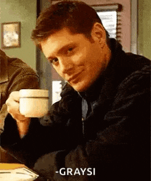 a man is sitting at a table with a cup of coffee .