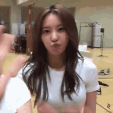 a woman in a white t-shirt is blowing a kiss .