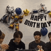 a happy birthday banner hangs from a wall with balloons