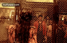 a woman is standing in front of a chain link fence in a cage .