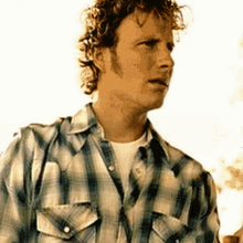 a man with curly hair and a plaid shirt