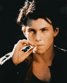 a young man is smoking a cigarette in a black jacket .