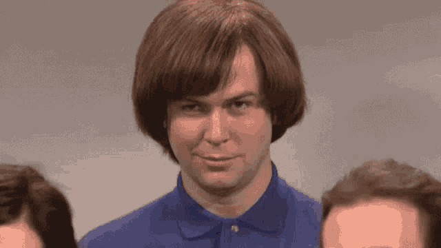 a man wearing a wig and a blue shirt is standing next to two other men