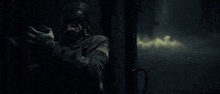 a man in a helmet is standing in a dark room with a gun .