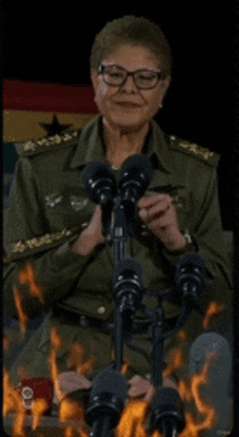 a woman in a military uniform is sitting in front of a row of microphones