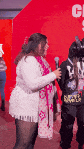 a person wearing a shirt that says never give up stands next to a woman holding a microphone