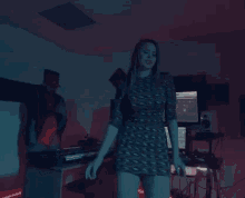 a woman is standing in a dark room in front of a keyboard and a computer .