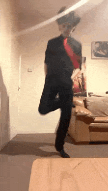 a man is dancing in a living room in front of a couch .