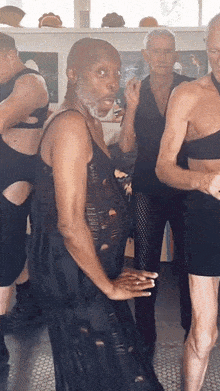 a group of men are standing in a room and one of them is wearing a black dress with holes in it