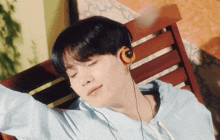 a young man wearing headphones is sitting on a wooden bench with his eyes closed