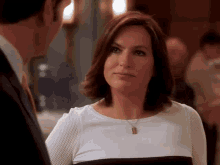 a woman in a white and black top is looking at a man in a suit and tie .