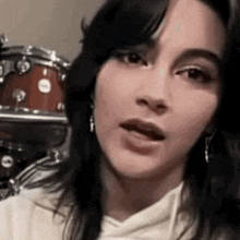 a close up of a woman 's face with a drum in the background .