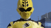a yellow power ranger is standing in front of a blue sky
