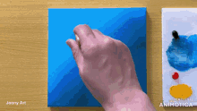 a person is painting on a blue canvas with a made in animatica logo