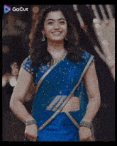 a woman in a blue saree is smiling and a gocut logo can be seen in the corner