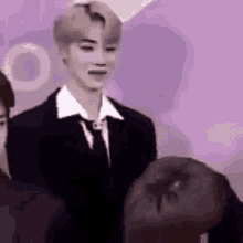 a man in a suit and tie is standing next to a woman in a purple room .