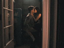 a man and woman are kissing in a doorway in a dark room .