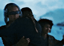 a woman wearing a blindfold is holding a child in her arms in a dark room .