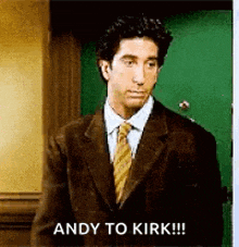 a man in a suit and tie is standing in front of a green door and says `` andy to kirk !!! ''
