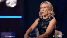 a woman is sitting in a chair with a nbc logo on the bottom right