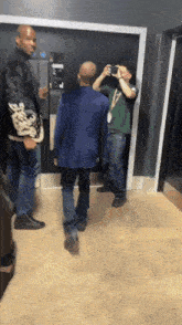 a man in a green shirt takes a picture of another man in a blue jacket