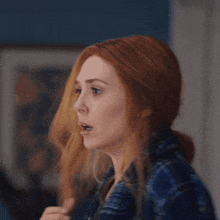 a woman with red hair is wearing a plaid shirt and making a surprised face