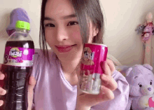 a young girl is holding a bottle of soda and a can of soda .