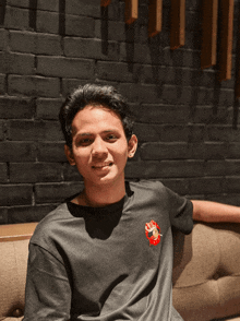 a young man sits on a couch wearing a t-shirt with a red circle on the front that says stop