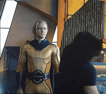 a man in a yellow superhero suit is standing next to another man