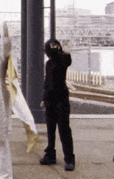 a man in a black suit is standing in front of a fence