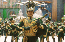 a man in a green and gold uniform is holding a cane in front of a band